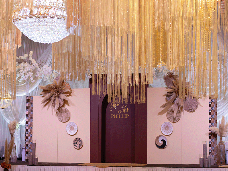 Pacific Islander wedding stage with gold tassels, pampas grass and tapa cloth columns
